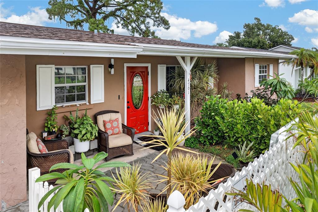 A tan house exterior features a red front door, a small patio, and white fencing — 4701 SPAHN STREET, SARASOTA, FL