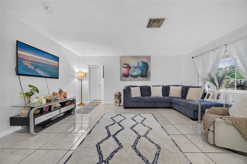 A living room features a blue sectional sofa, a patterned area rug, and tile flooring — 4701 SPAHN STREET, SARASOTA, FL