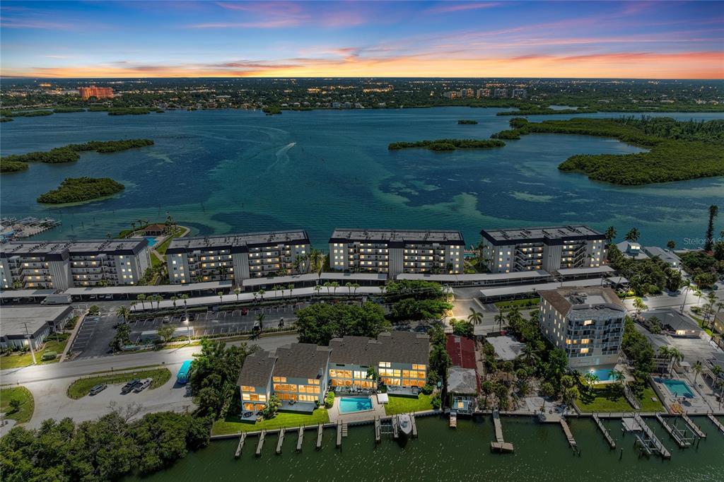 An aerial view shows waterfront residential buildings, a swimming pool, and a boat dock — 8977 MIDNIGHT PASS ROAD UNIT 219, SARASOTA, FL