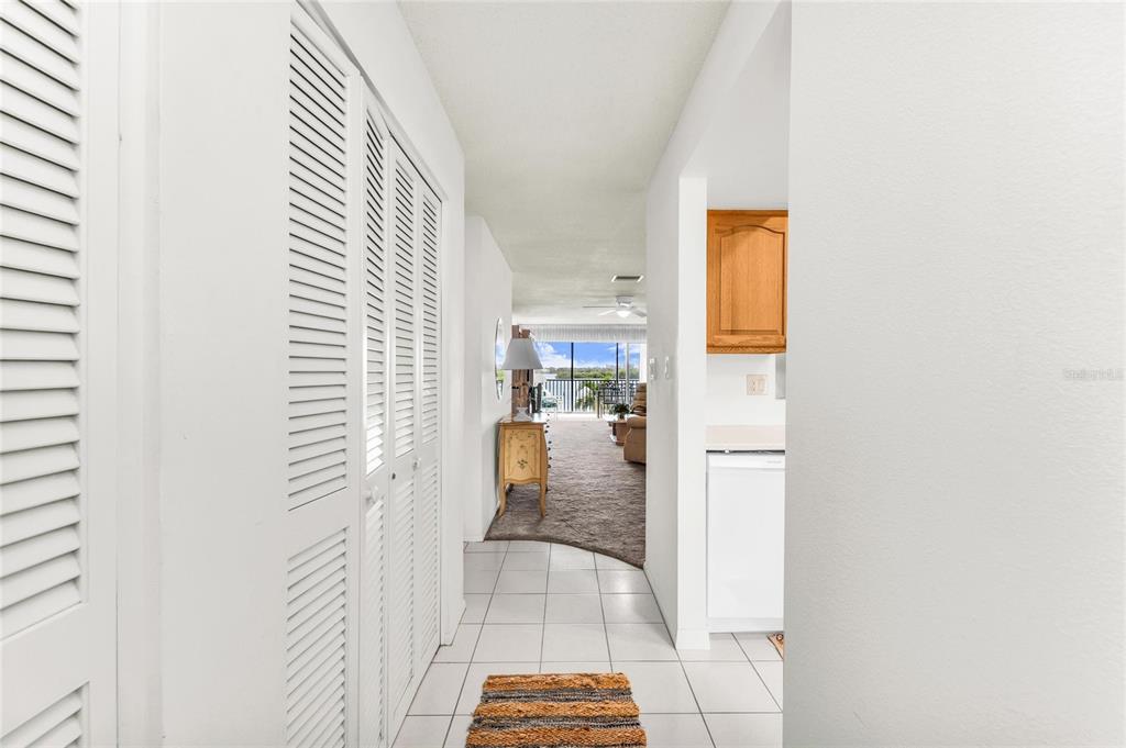 A tiled hallway leads past a white louvered closet toward a carpeted living area — 8977 MIDNIGHT PASS ROAD UNIT 219, SARASOTA, FL