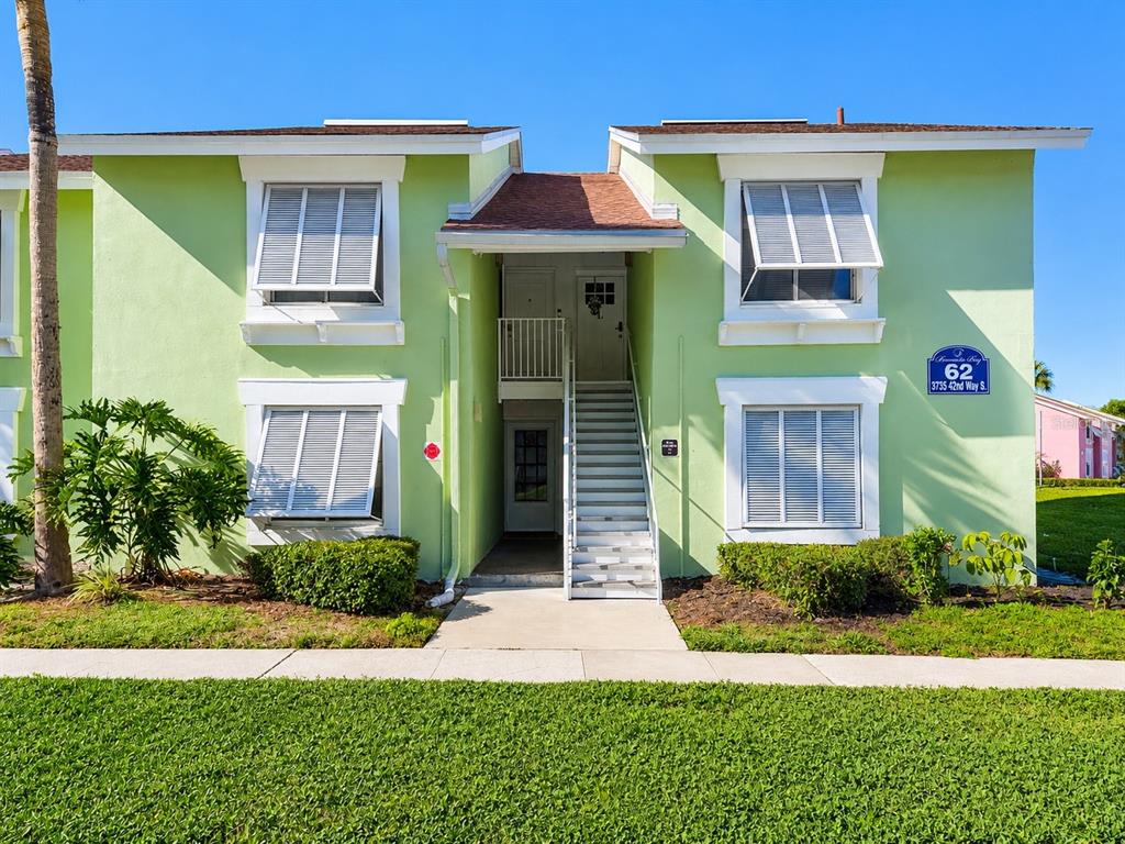 A two-story light green apartment building with white shutters and an exterior staircase — 3735 42ND WAY S UNIT E, ST PETERSBURG, FL