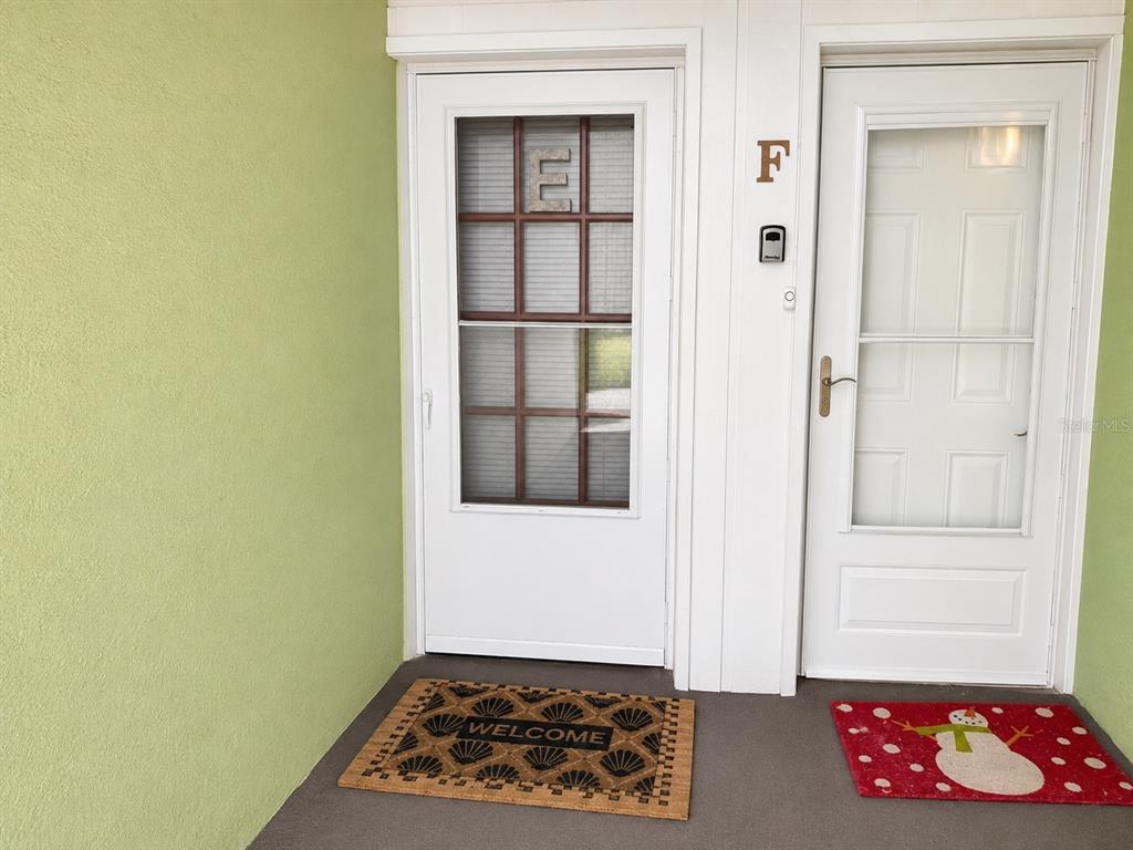A dining area with a glass table and four chairs sits before a sliding glass door — 3735 42ND WAY S UNIT E, ST PETERSBURG, FL