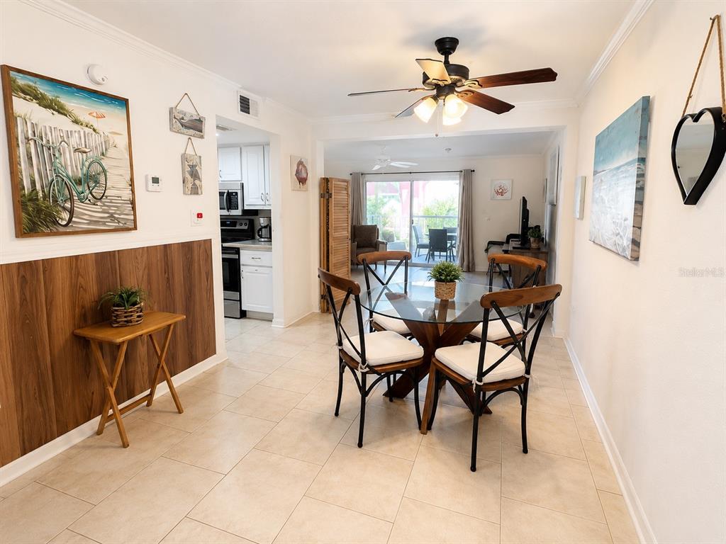 A living and dining area with tile flooring, a ceiling fan, and coastal-themed wall decor — 3735 42ND WAY S UNIT E, ST PETERSBURG, FL