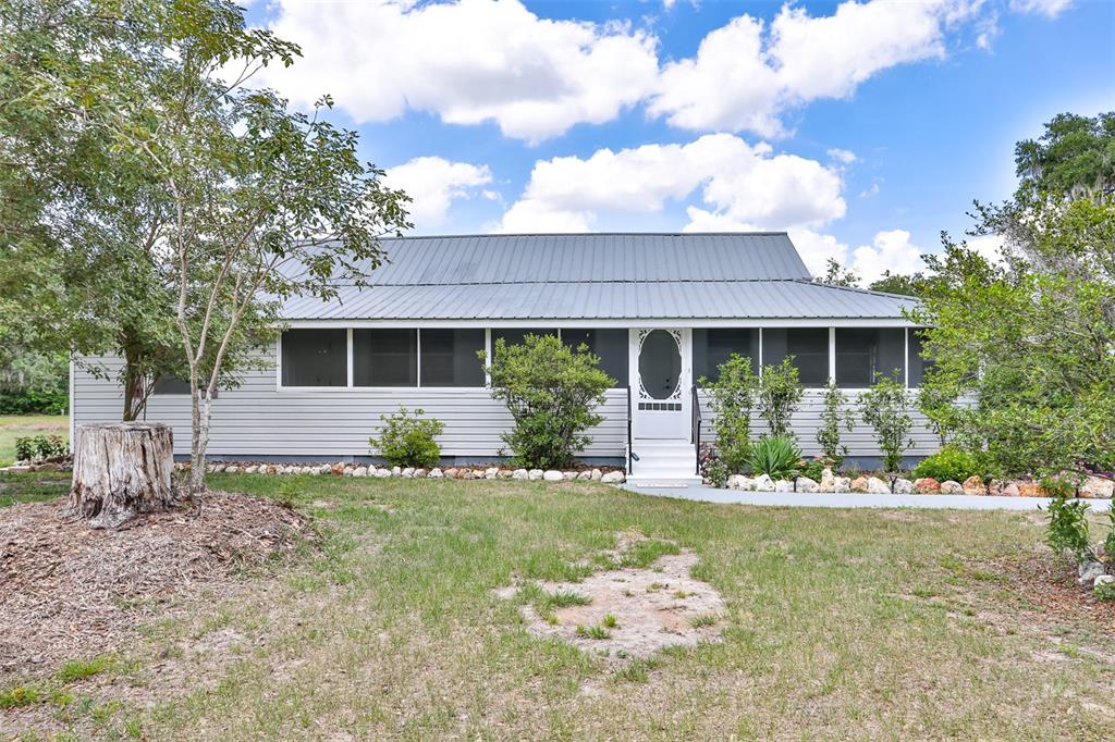 A single-story house with gray siding, a metal roof, and a screened-in front porch — 610 LYLE PARKWAY, BARTOW, FL