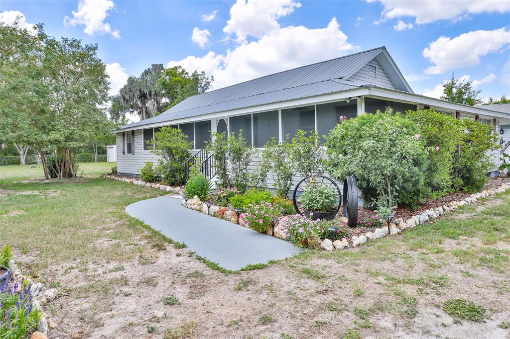 A single-story house with a metal roof and a screened porch sits on a lawn — 610 LYLE PARKWAY, BARTOW, FL