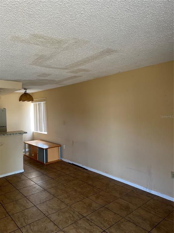A living room with tiled floors, a beige wall, and a stained popcorn ceiling — 800 N FISKE BOULEVARD UNIT 606, COCOA, FL