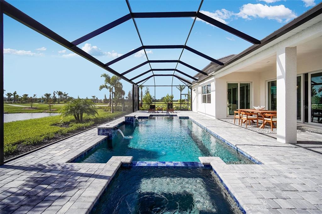 A screened-in patio features a rectangular swimming pool, a hot tub, and outdoor dining furniture — 20009 TROUT TERRACE, LAKEWOOD RANCH, FL