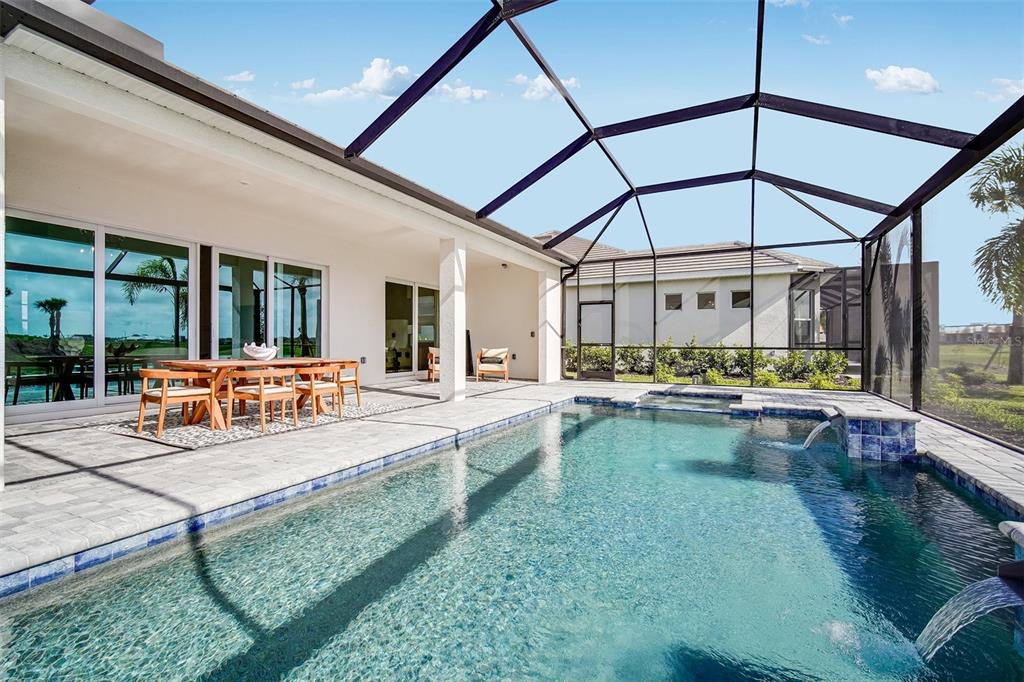 A screened-in patio features a swimming pool with a spa and an outdoor dining area — 20009 TROUT TERRACE, LAKEWOOD RANCH, FL