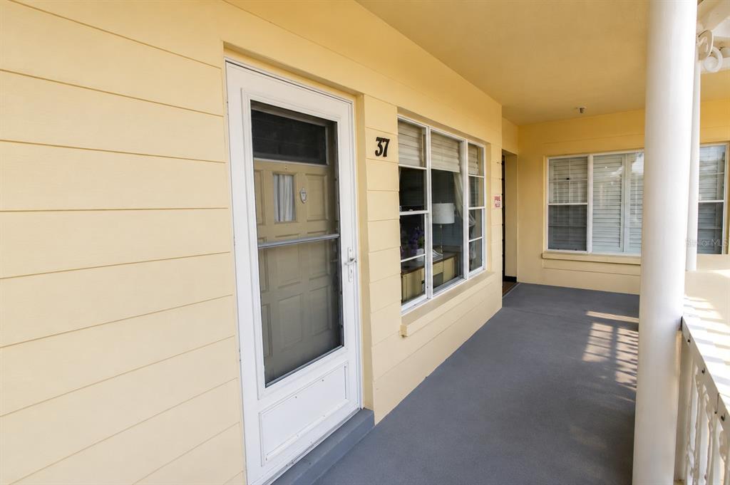 A yellow exterior wall features a white front door, a window, and a covered porch — 2459 FRANCISCAN DRIVE UNIT 37, CLEARWATER, FL
