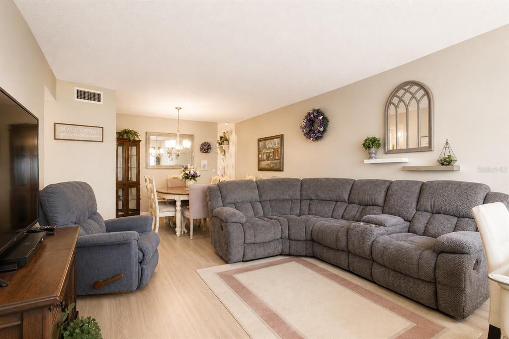 A living room features a large gray sectional sofa, a recliner, and an adjacent dining area — 2459 FRANCISCAN DRIVE UNIT 37, CLEARWATER, FL