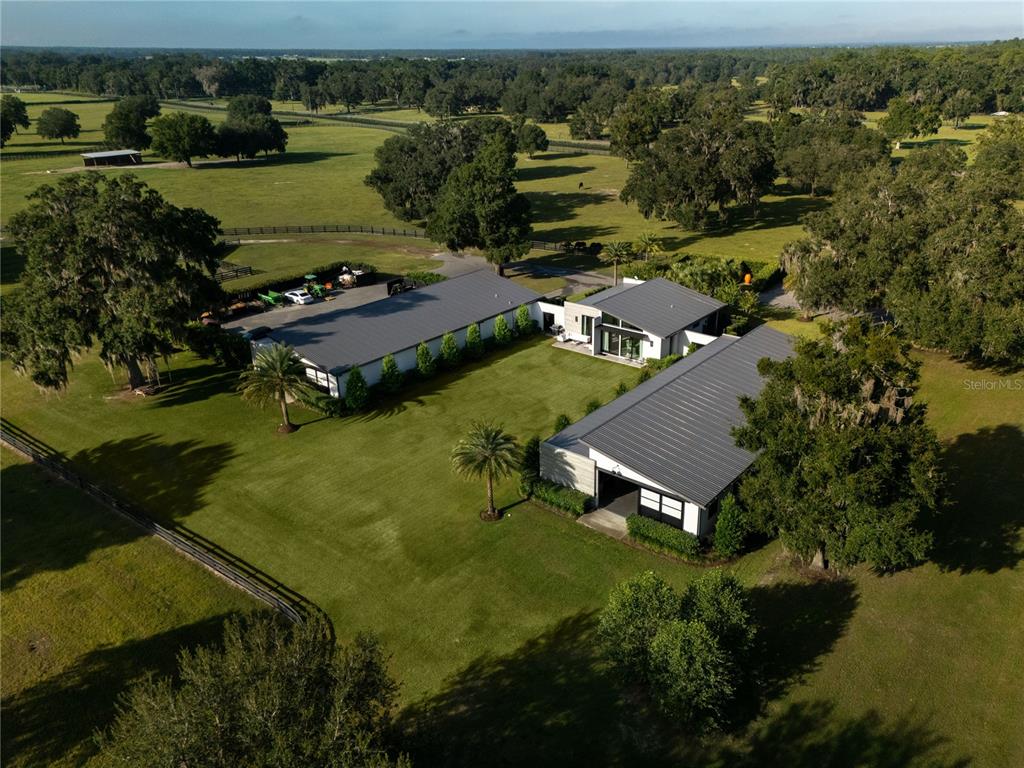 An aerial view shows a modern house with two large outbuildings on a grassy lot — 2875 NW 150TH AVENUE, OCALA, FL