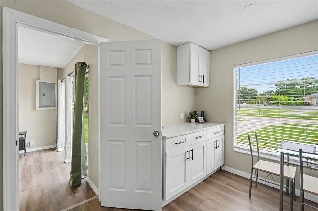 A room with white cabinets, a countertop, a window, and a door leading to another room — 102 SHORE DRIVE E, OLDSMAR, FL