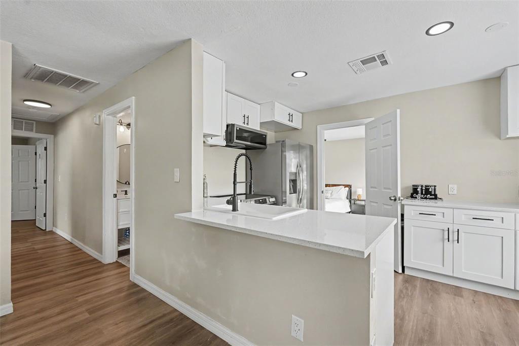 A kitchen with white cabinets, a quartz breakfast bar, and stainless steel appliances — 102 SHORE DRIVE E, OLDSMAR, FL