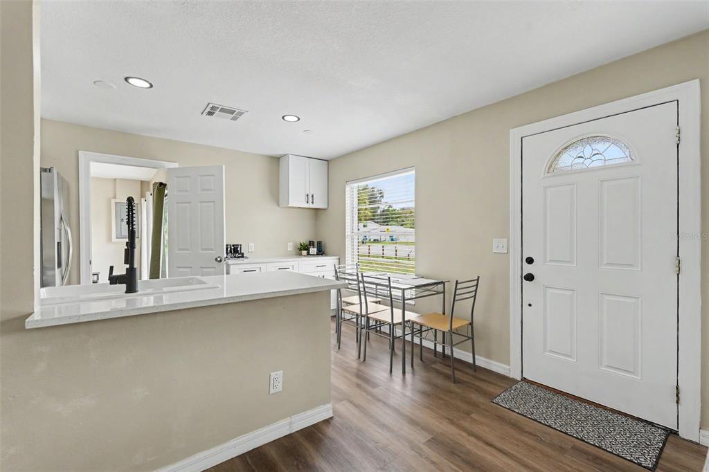 A kitchen with a breakfast bar, dining area, and front door on a wood floor — 102 SHORE DRIVE E, OLDSMAR, FL