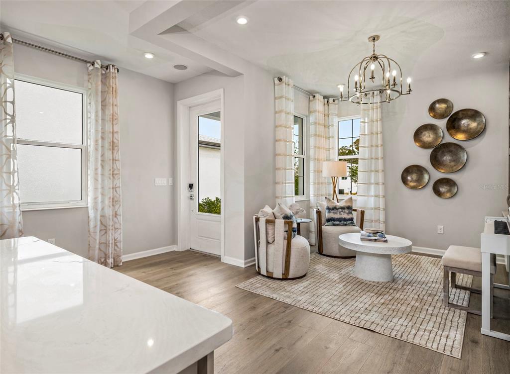 A bright living area features wood-look flooring, a white marble island, and a decorative wall display — 419 VERONA WAY, LADY LAKE, FL
