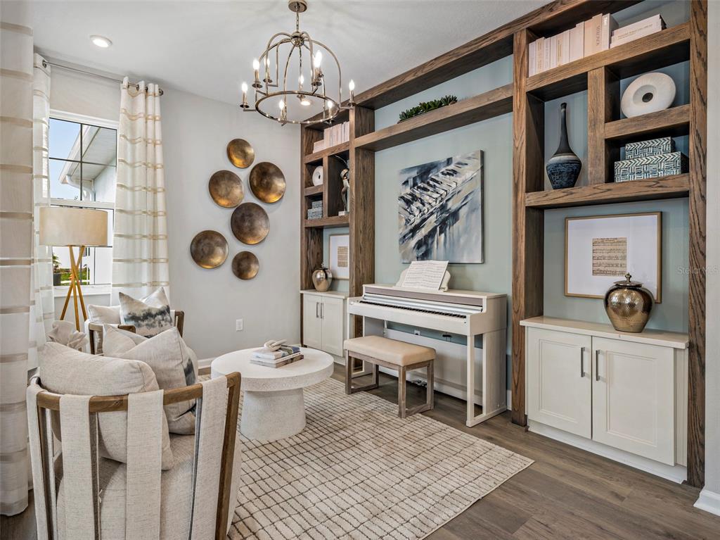A living room features a white piano, built-in wooden shelving, and two armchairs on a rug — 419 VERONA WAY, LADY LAKE, FL
