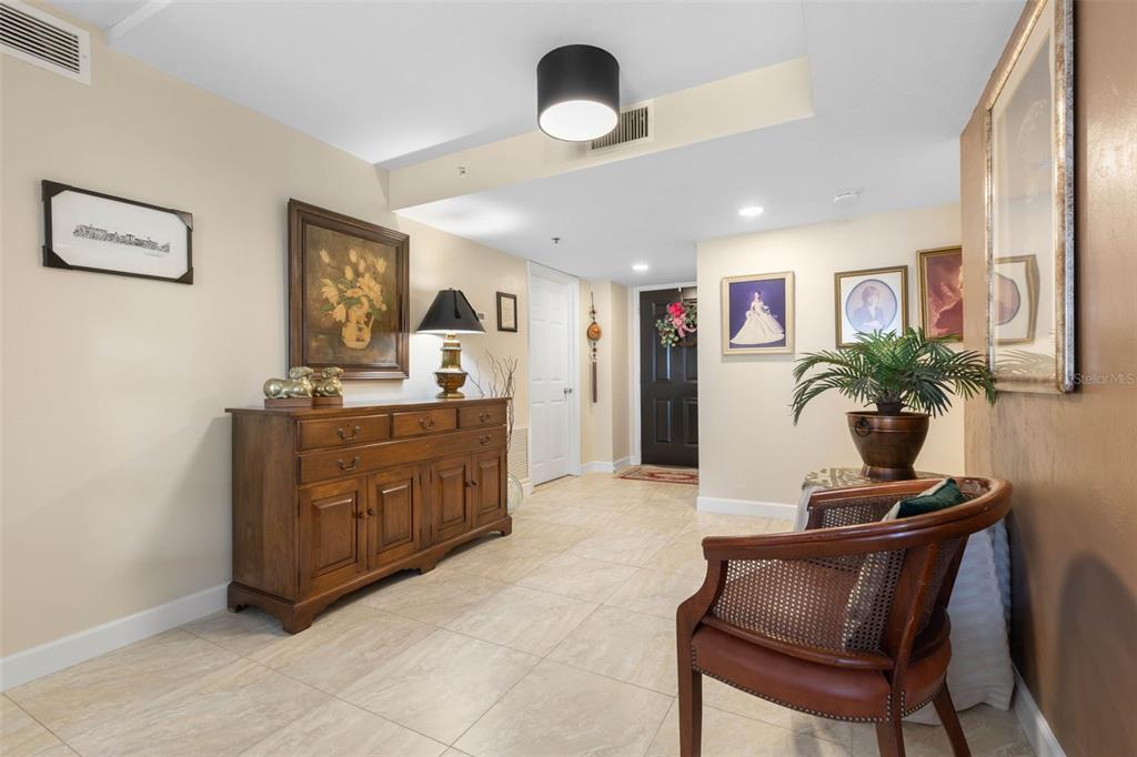 An entryway features a wooden sideboard, a cane-back chair, tiled floors, and several framed pictures — 1 JOHN ANDERSON DRIVE UNIT 5160, ORMOND BEACH, FL
