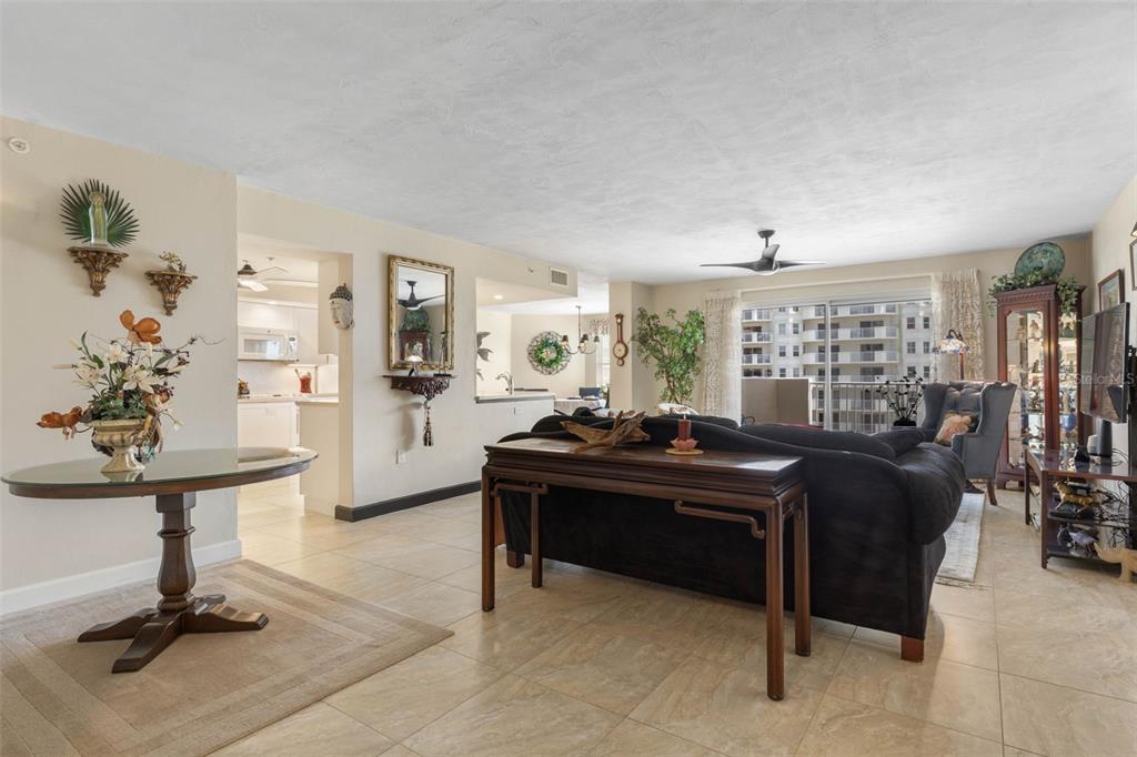 A living room with tile floors, a dark sofa, and a glass-topped entry table — 1 JOHN ANDERSON DRIVE UNIT 5160, ORMOND BEACH, FL
