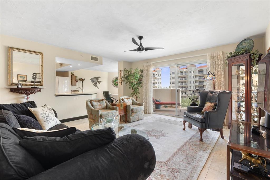 A living room with a black sofa, two patterned armchairs, and a balcony overlooking buildings — 1 JOHN ANDERSON DRIVE UNIT 5160, ORMOND BEACH, FL
