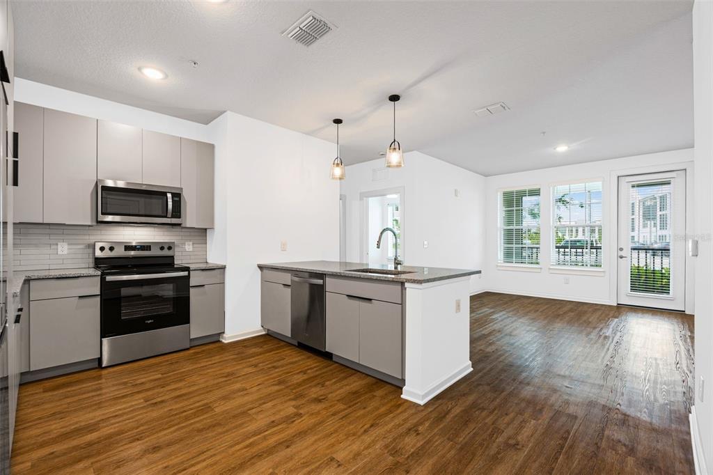 A modern kitchen with grey cabinets, stainless steel appliances, and an island with a sink — 1700 RANCH ROAD UNIT B1-10312, NOKOMIS, FL