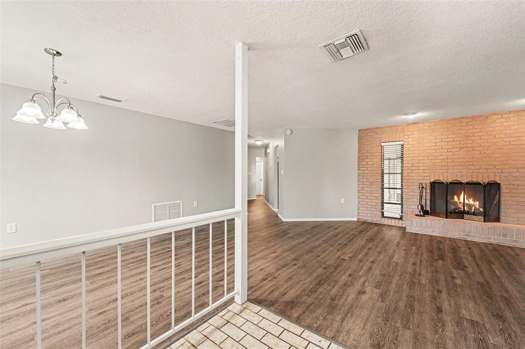 A living room with wood-look flooring opens to a kitchen with white cabinets and counters — 8321 BRIARLEAF COURT, PORT RICHEY, FL