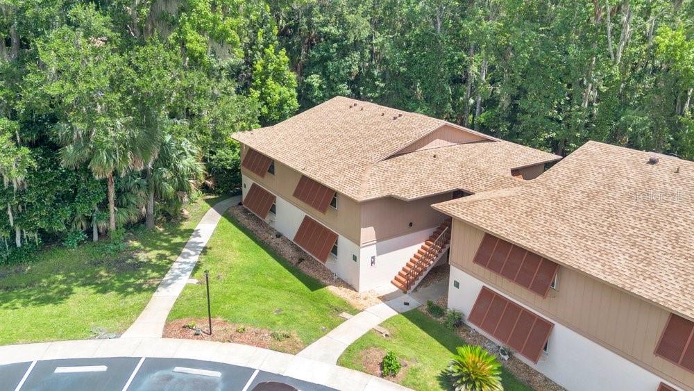 An aerial view of a two-story apartment building with brown shutters and a shingled roof — 150 WAX MYRTLE WOODS COURT UNIT 9B, DELTONA, FL