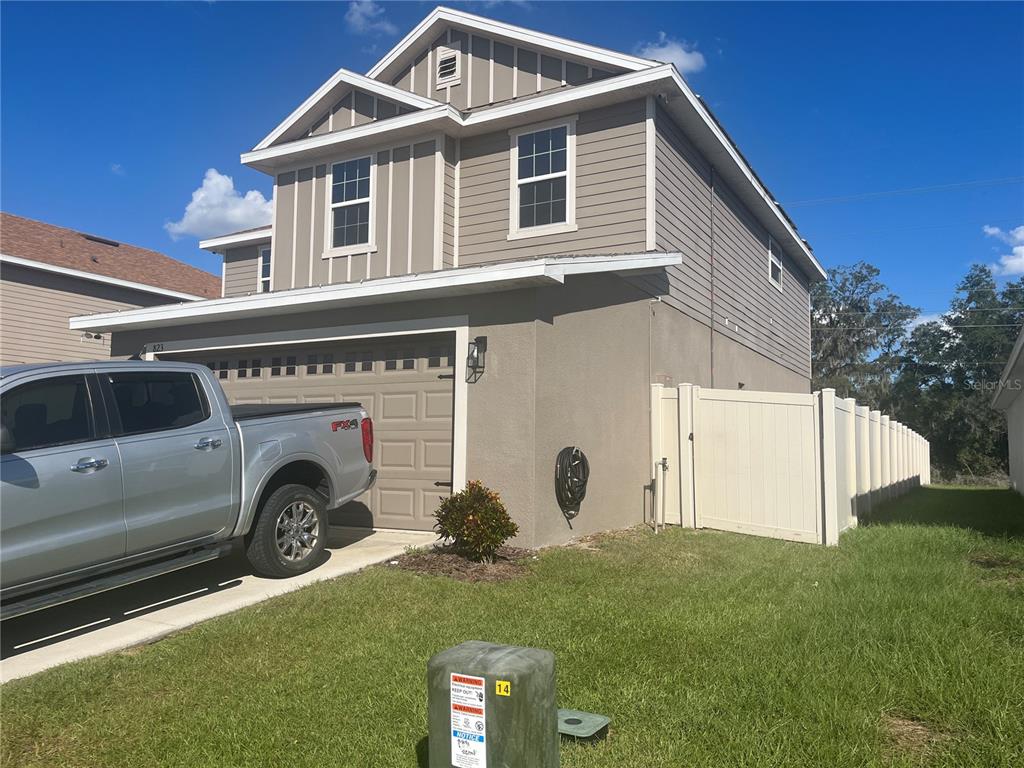 A two-story house with a gray exterior, a two-car garage, and a white vinyl fence — 823 CHINOY ROAD, DAVENPORT, FL