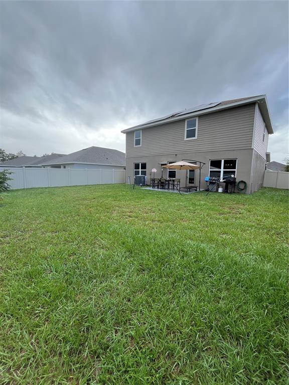 The backyard features a grassy lawn, a concrete patio, and a two-story house exterior — 823 CHINOY ROAD, DAVENPORT, FL