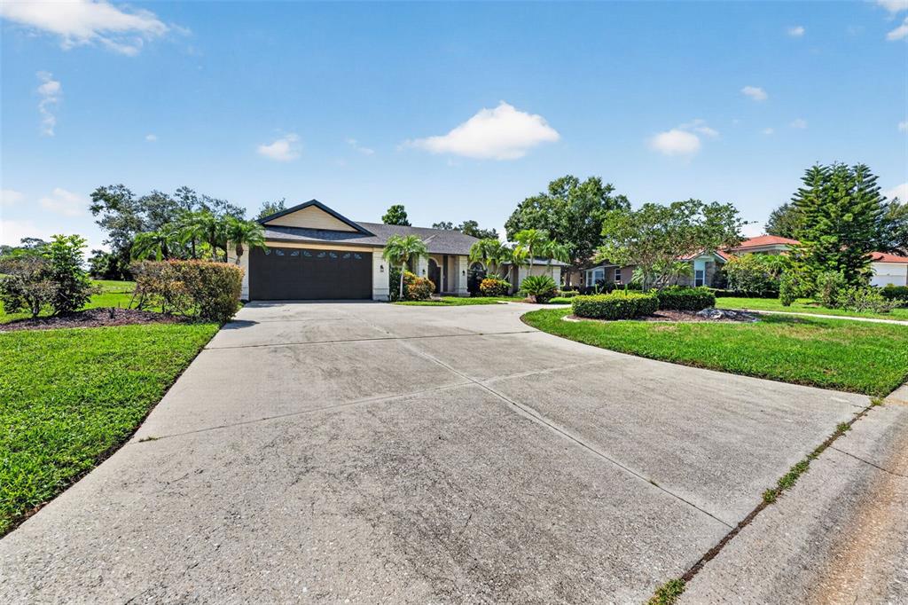 A single-story house with a large concrete driveway and a dark garage door — 2941 WILDERNESS BOULEVARD E, PARRISH, FL