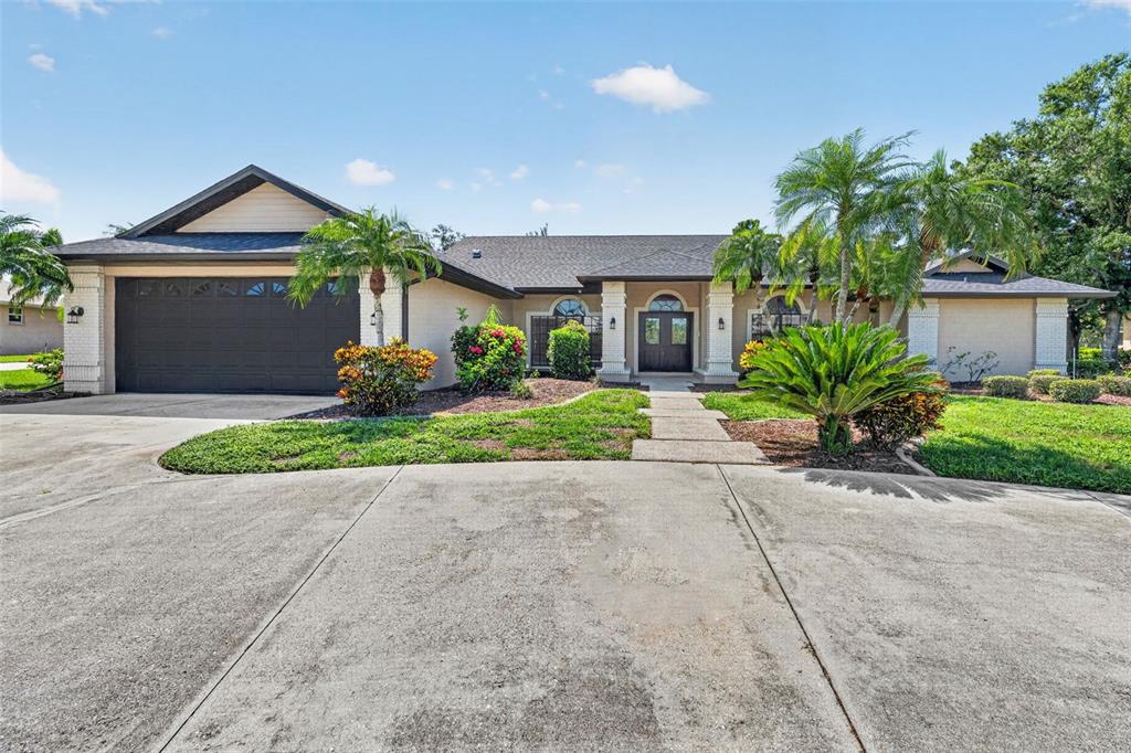 A single-story house with a two-car garage, beige stucco exterior, and a concrete driveway — 2941 WILDERNESS BOULEVARD E, PARRISH, FL