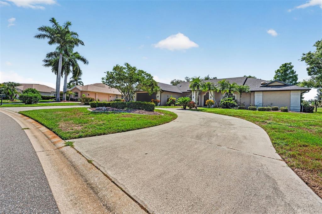 A single-story house with a concrete driveway, palm trees, and a landscaped front lawn — 2941 WILDERNESS BOULEVARD E, PARRISH, FL