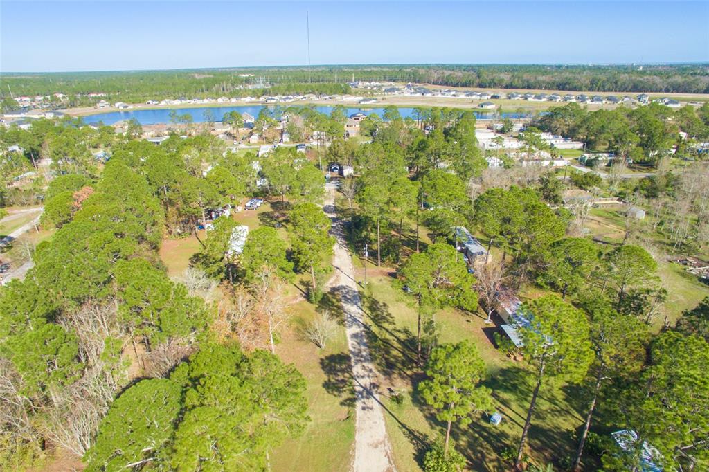 An aerial view shows a dirt road winding through a wooded lot with several mobile homes — 1211 CYPRESS ROAD, ST AUGUSTINE, FL