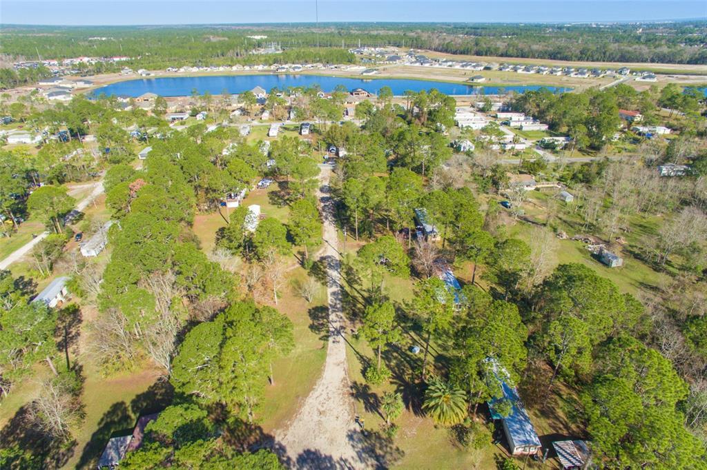 An aerial view shows a dirt road winding through a wooded area with scattered mobile homes — 1211 CYPRESS ROAD, ST AUGUSTINE, FL