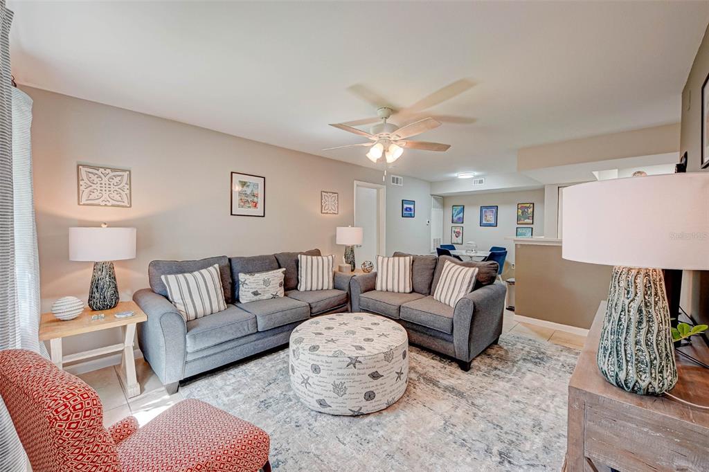A living room features two gray sofas, a patterned ottoman, and a large area rug — 3038 PARKWAY BOULEVARD UNIT 305, KISSIMMEE, FL