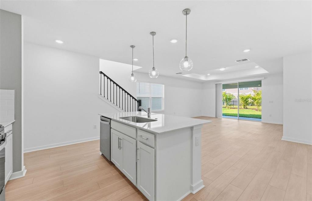 A kitchen island with a sink sits in an open-concept room with light wood flooring — 5322 SPRING MAIDEN CIRCLE, APOLLO BEACH, FL