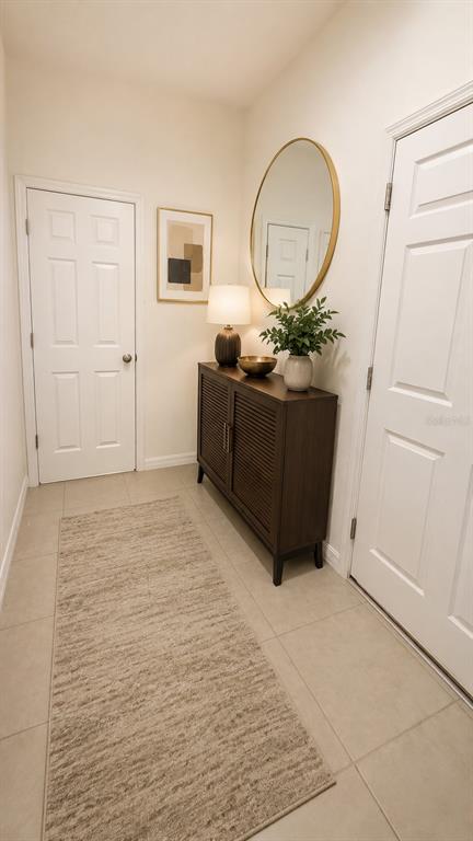 A bright entryway features a dark wood cabinet, a round gold mirror, and a runner rug — 4420 GUMBO LIMBO DRIVE, ORLANDO, FL