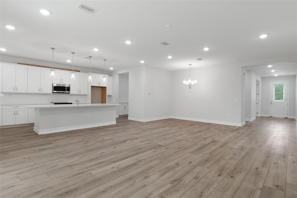 A bright, open-concept kitchen and living area featuring white cabinetry, a large island, and wood-look flooring — 6162 W CONESTOGA STREET, BEVERLY HILLS, FL