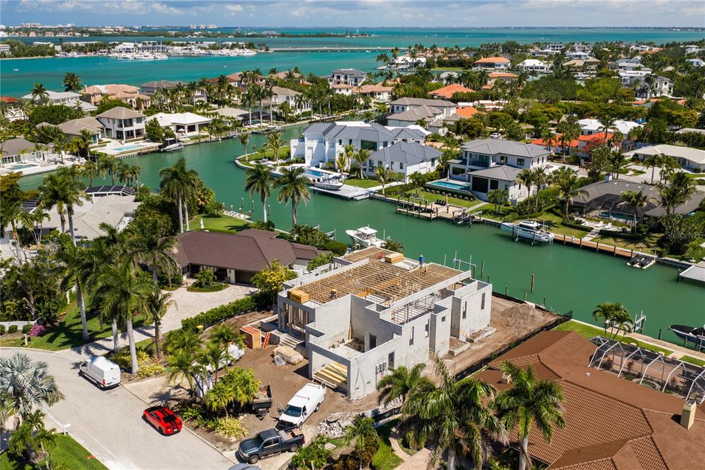 An aerial view shows a house under construction next to a canal with docked boats — 526 N SPOONBILL DRIVE, SARASOTA, FL