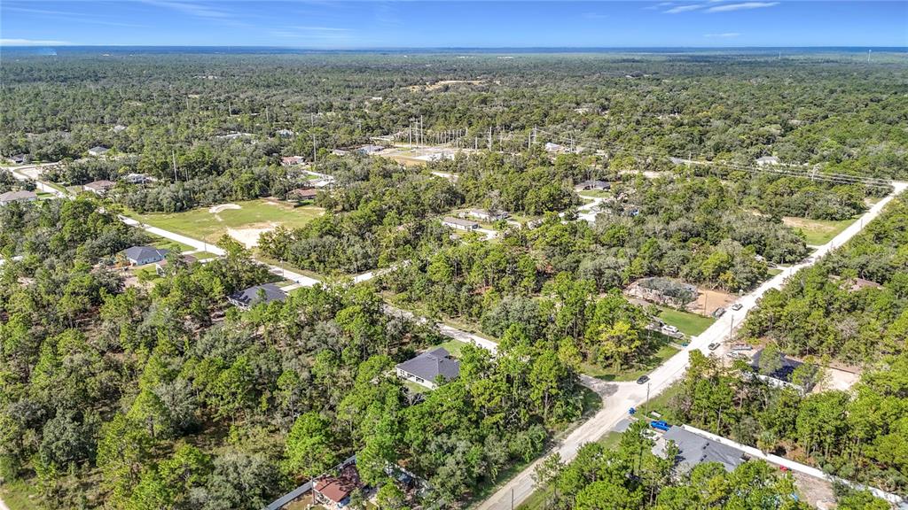 An aerial view shows several houses scattered among dense trees and dirt roads — 13542 ROBIN AVENUE, WEEKI WACHEE, FL