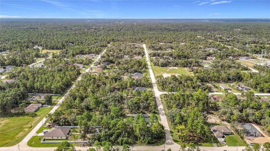 An aerial view shows houses scattered among dense trees along paved residential streets — 13542 ROBIN AVENUE, WEEKI WACHEE, FL