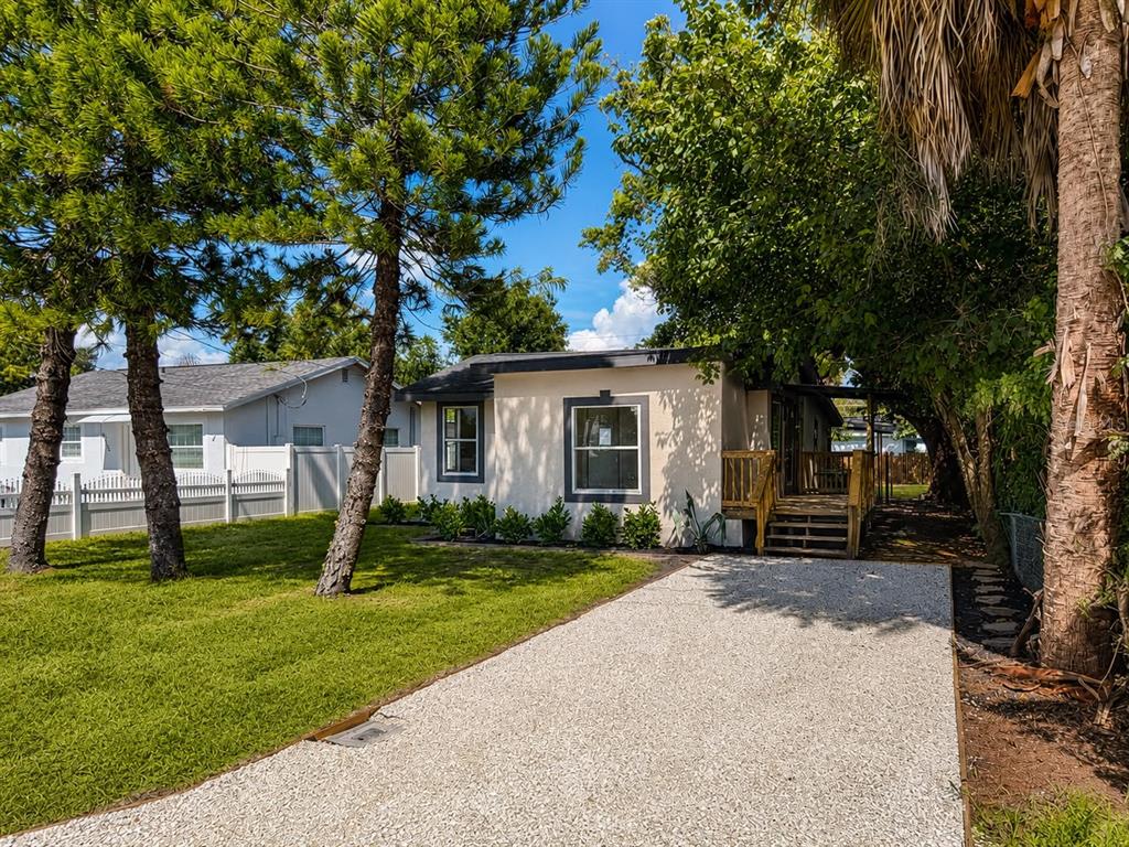 A single-story house with a white stucco exterior, two front windows, and a wooden porch — 8713 N EDISON AVENUE, TAMPA, FL