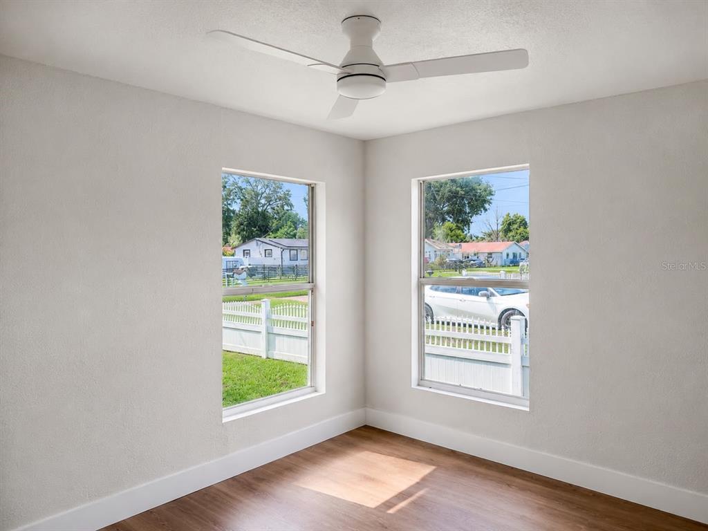 A small, light-colored house with a gravel driveway, wooden deck, and several tall pine trees — 8713 N EDISON AVENUE, TAMPA, FL