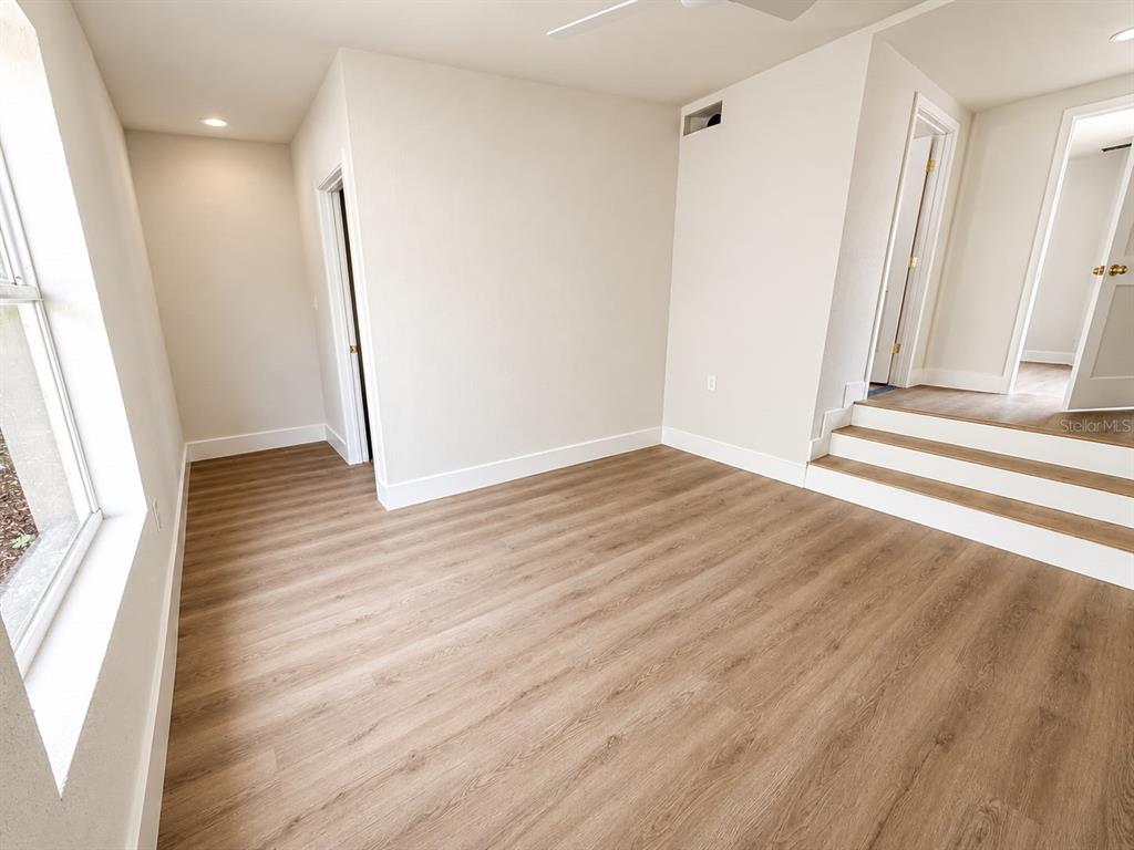 A living room with light wood floors, a modern chandelier, and a black console table — 8713 N EDISON AVENUE, TAMPA, FL