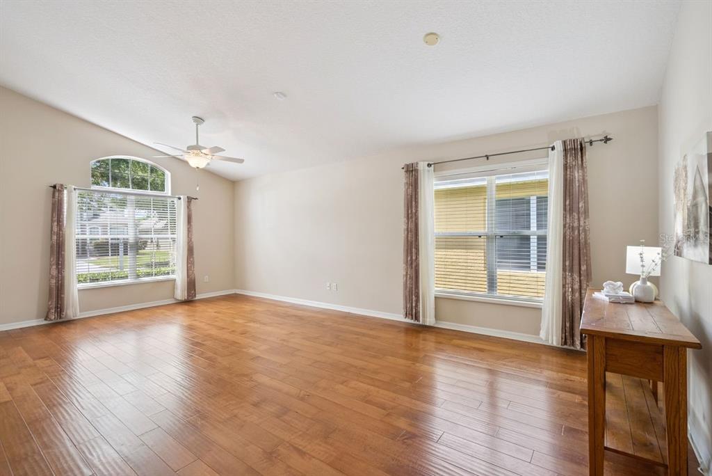 A spacious living room with hardwood floors, a ceiling fan, and two large windows — 5345 LOS PALMA VISTA DRIVE, ORLANDO, FL