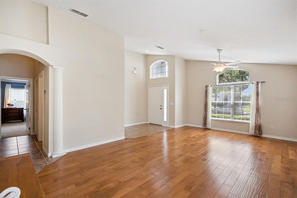 A living room with hardwood floors, a vaulted ceiling, a ceiling fan, and an entryway — 5345 LOS PALMA VISTA DRIVE, ORLANDO, FL