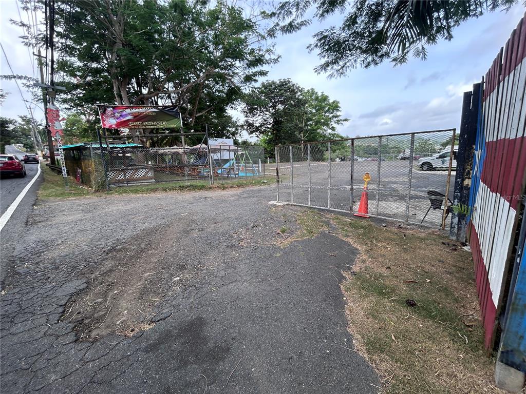An outdoor gravel parking area is enclosed by a metal fence next to a road — PR 842 CAIMITO ALTO, SAN JUAN, PR