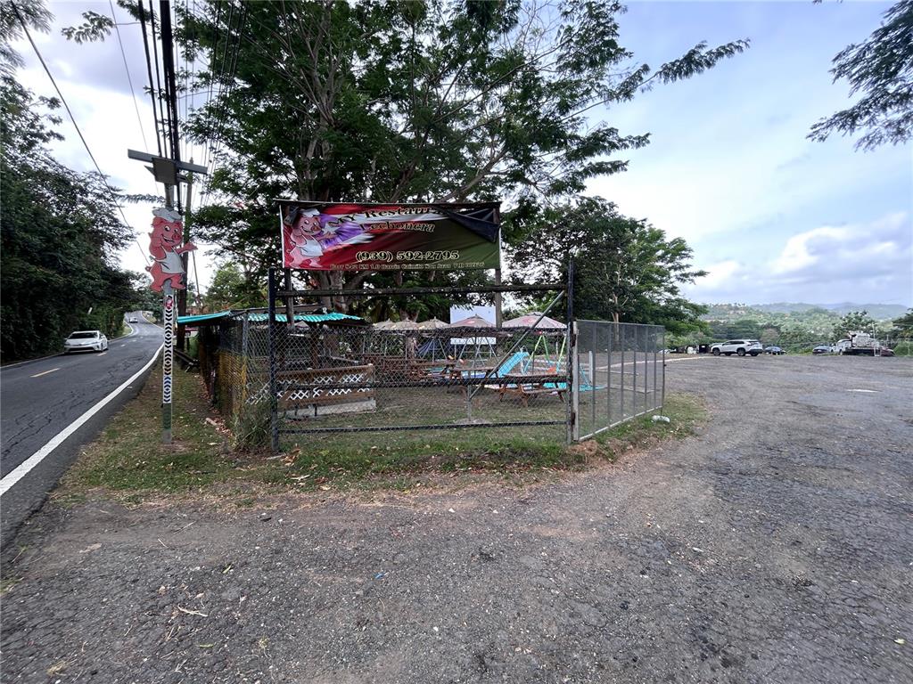 An outdoor restaurant area features a fenced playground and a sign with a phone number — PR 842 CAIMITO ALTO, SAN JUAN, PR