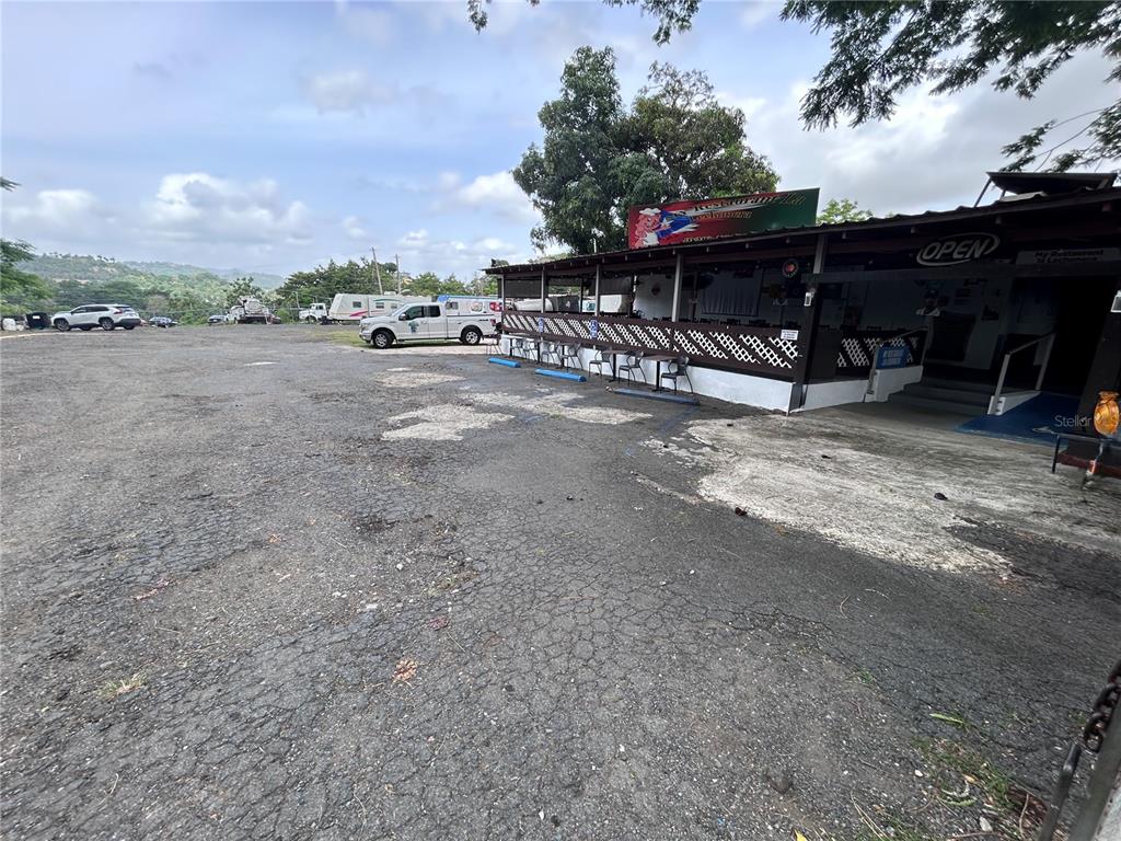 A gravel parking lot sits in front of a restaurant with a covered outdoor seating area — PR 842 CAIMITO ALTO, SAN JUAN, PR