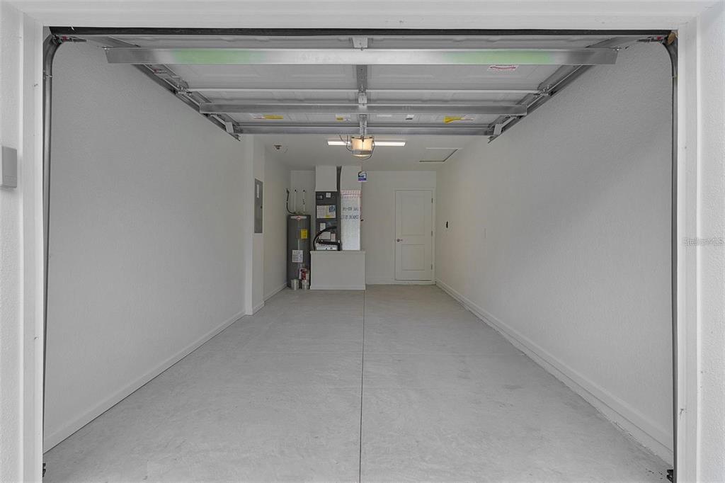 An empty, single-car garage with white walls, a concrete floor, and an exposed water heater — 14 FISHER LOOP TRACE, OCKLAWAHA, FL