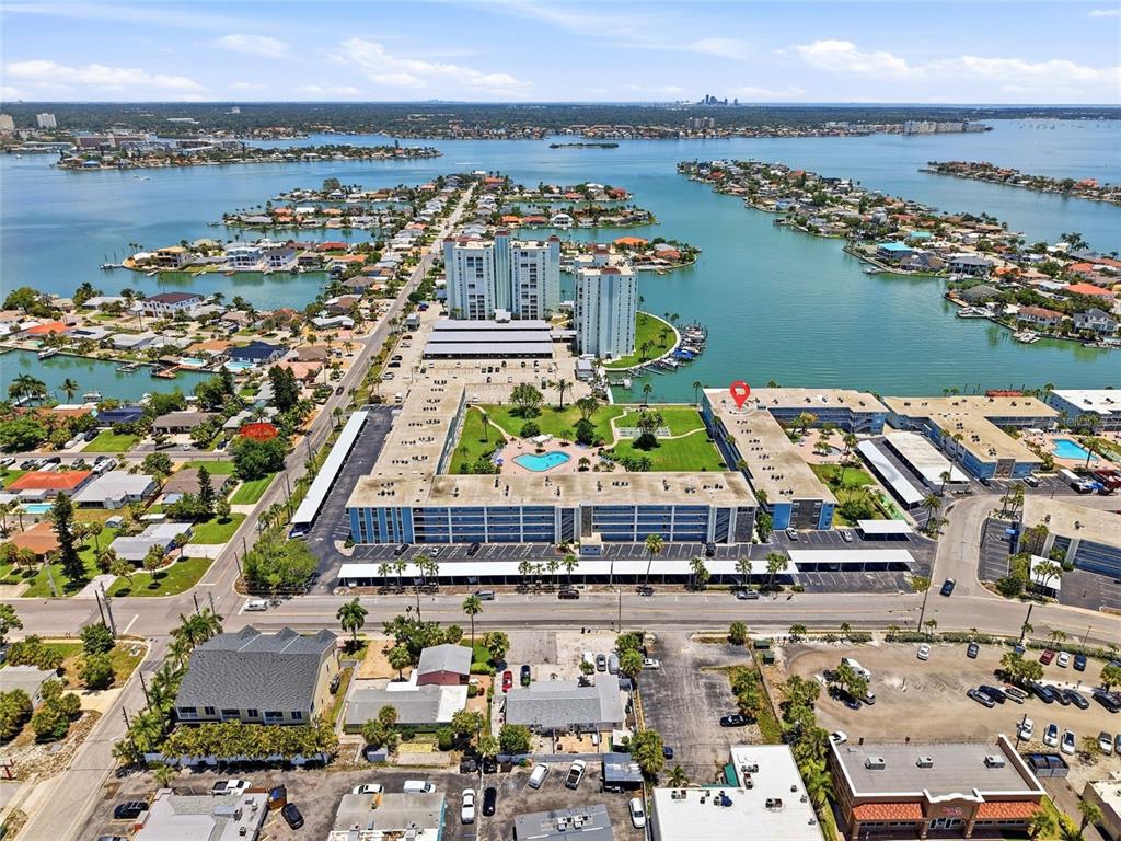 An outdoor walkway overlooks a courtyard with a swimming pool, palm trees, and a court — 6201 2ND STREET E UNIT 106, ST PETE BEACH, FL